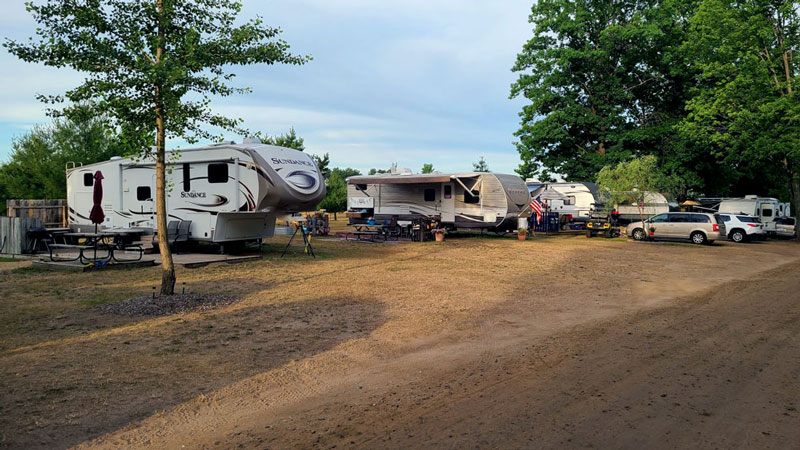 This is a photo of Evergreen Park with a few campers set up along a dirt road.