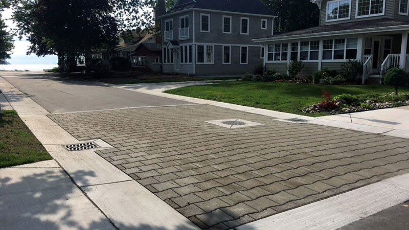 This is a photo of a brick paver street with homes in the background and a lake off in the distance. This was a job from BMJ Engineers & Surveyors, Inc. at Forrest Manor.